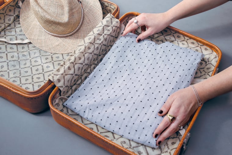 Place clothing into the suitcase Place clothing into the suitcase